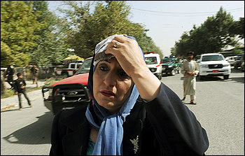 A woman leaves the scene after a car bomb exploded outside NATO Headquarters in Kabul, Afghanistan, on Saturday, August 15, 2009. 